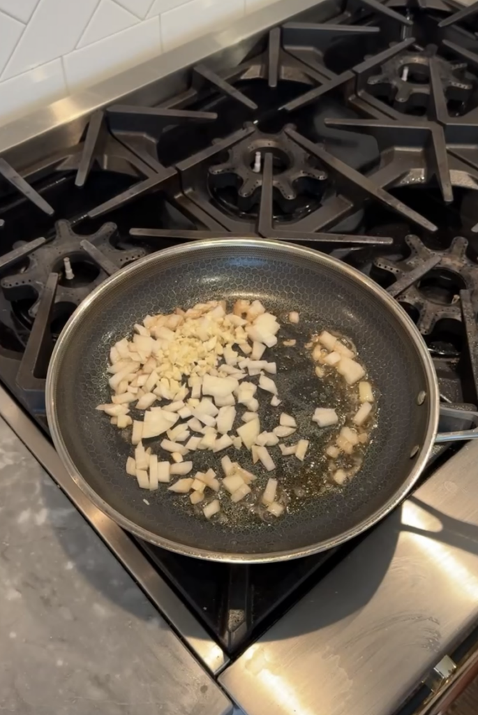 Saucepan on stove with butter, garlic and onions cooking.