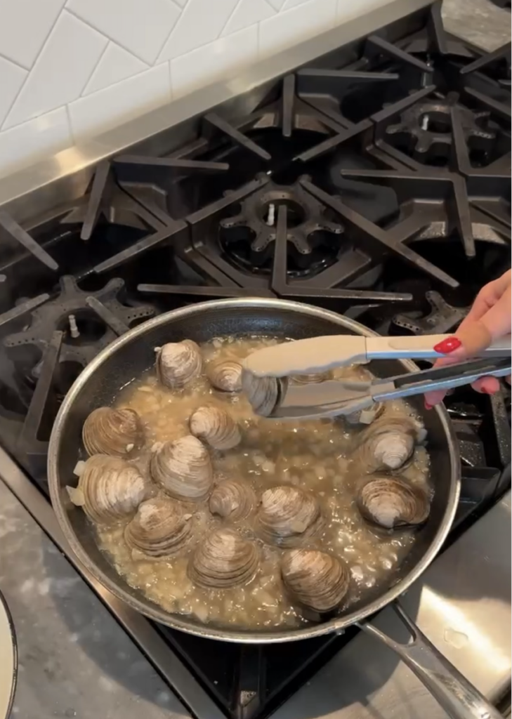 Saucepan filed with white wine and littleneck clams.