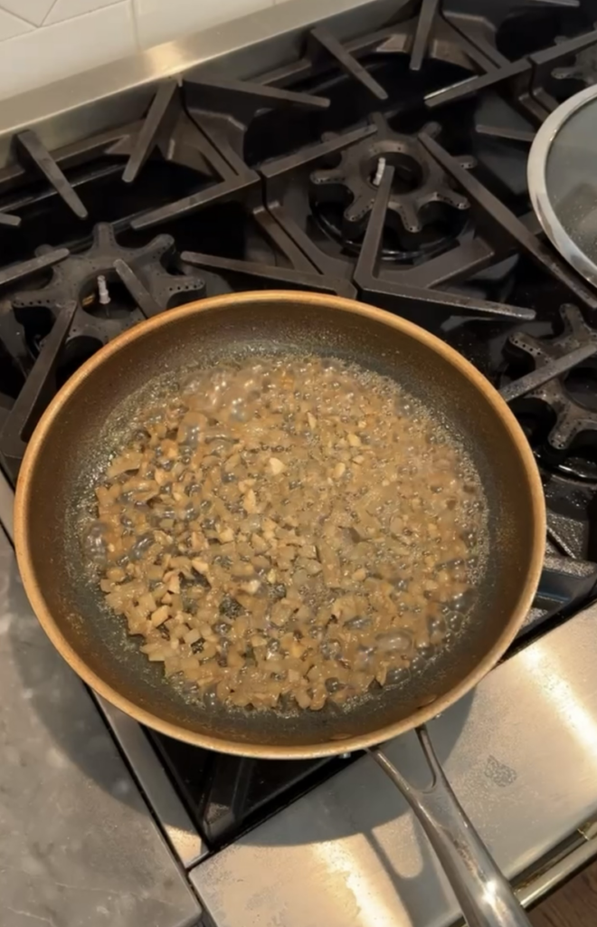 Reduced white wine broth with onions and garlic in saucepan.