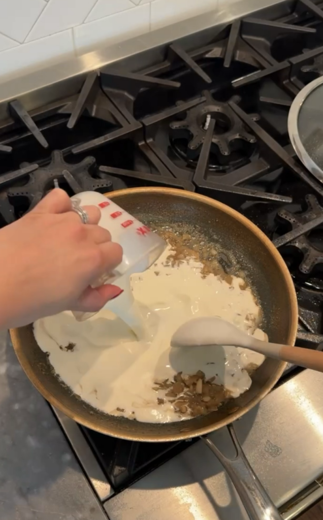 Heavy cream being poured into saucepan.