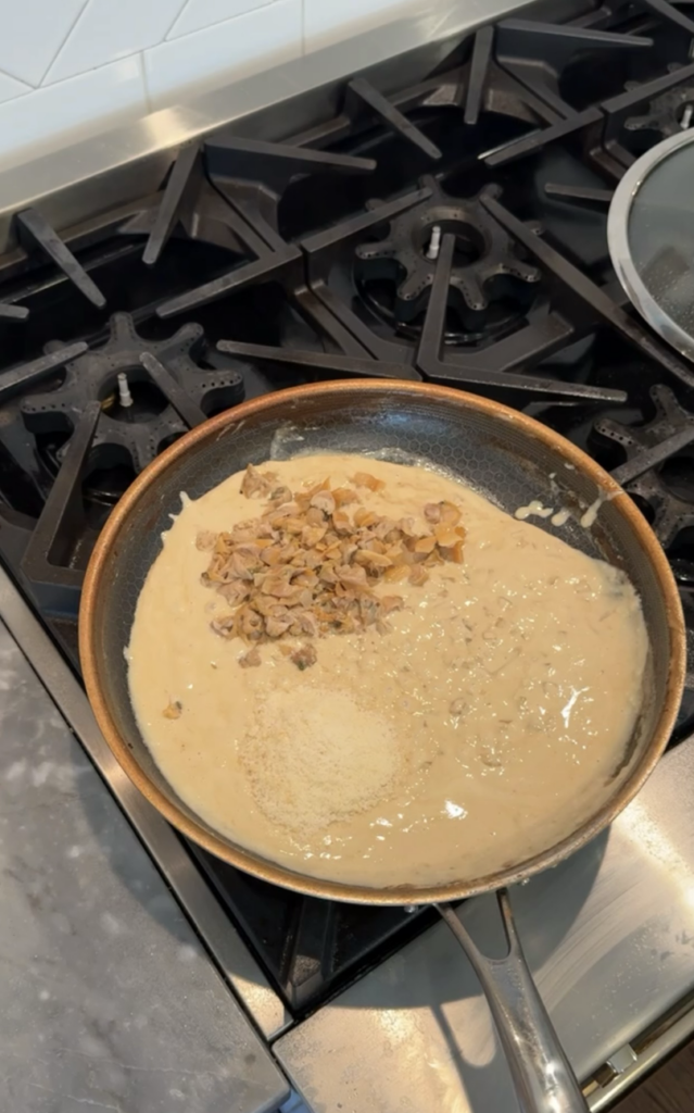 Chopped clams and Parmesan cheese added to saucepan.