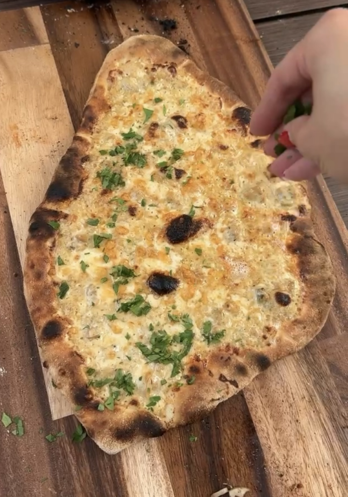 Final result of pizza with parsley sprinkled on top.