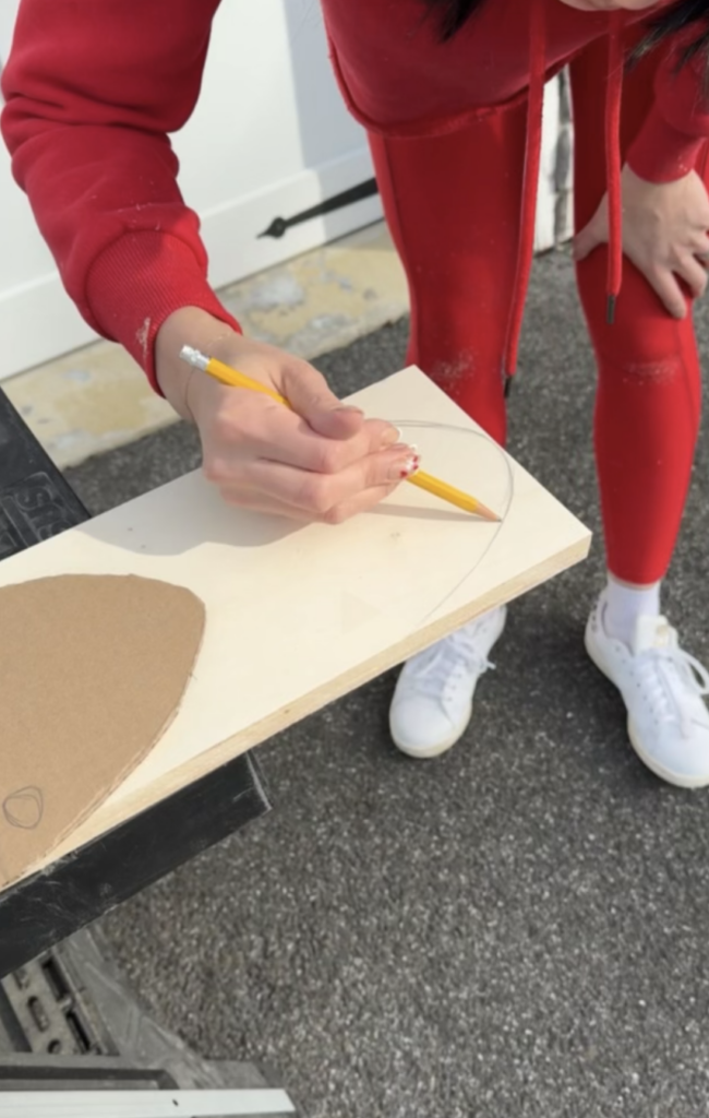 Plywood being traced with pencil for an oval shape. 