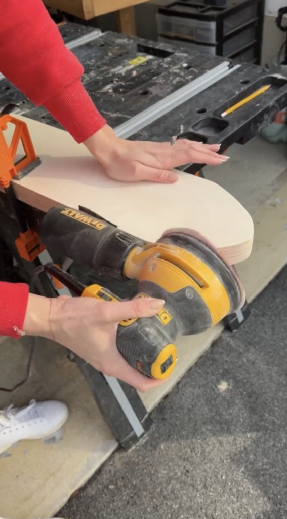 Plywood in oval shape being sanded down. 