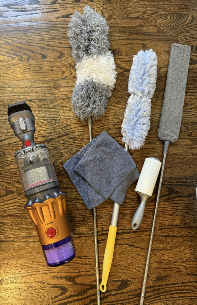 Dusting cleaning supplies laid out on hardwood floor.