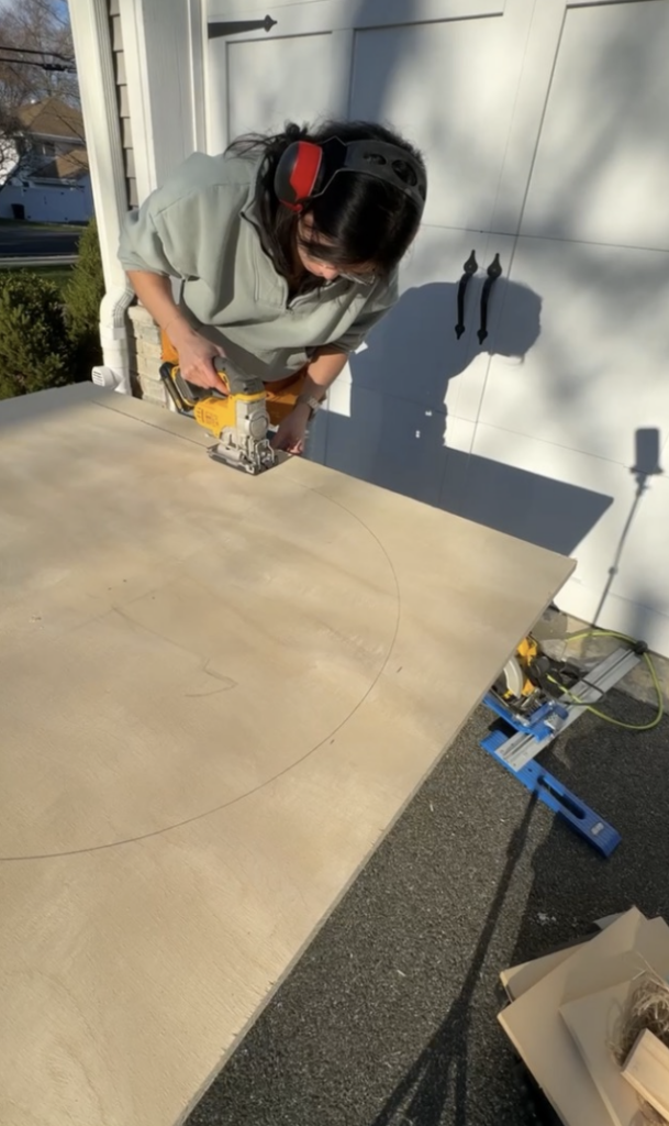 Jigsaw cutting archway on plywood outside.